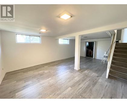 A spacious room with wooden flooring and a staircase leading to another room.