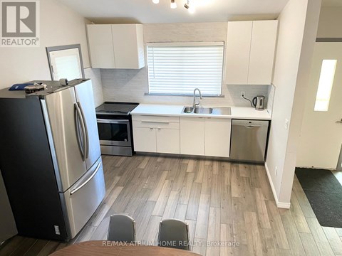 A kitchen with white cabinets and a black refrigerator.