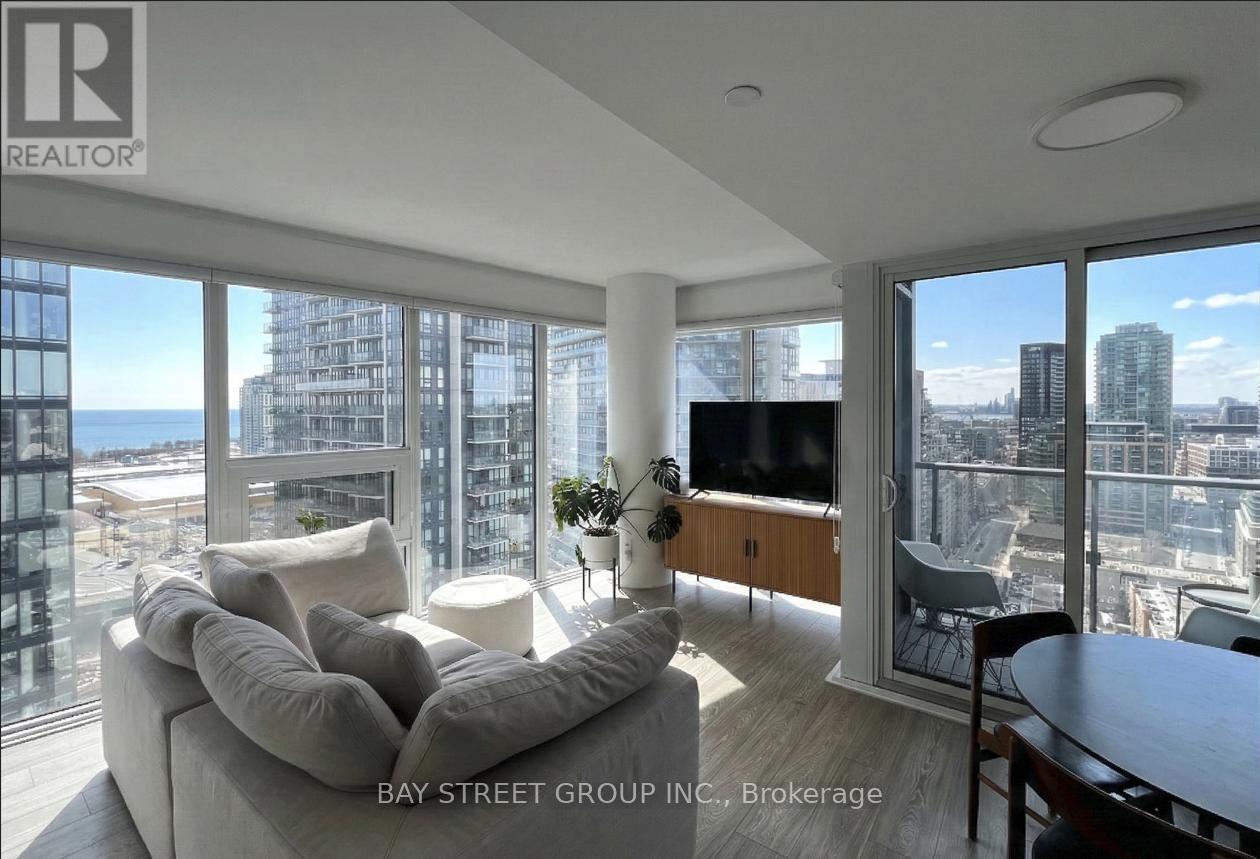 A living room with a couch, a television, and a view of the city.