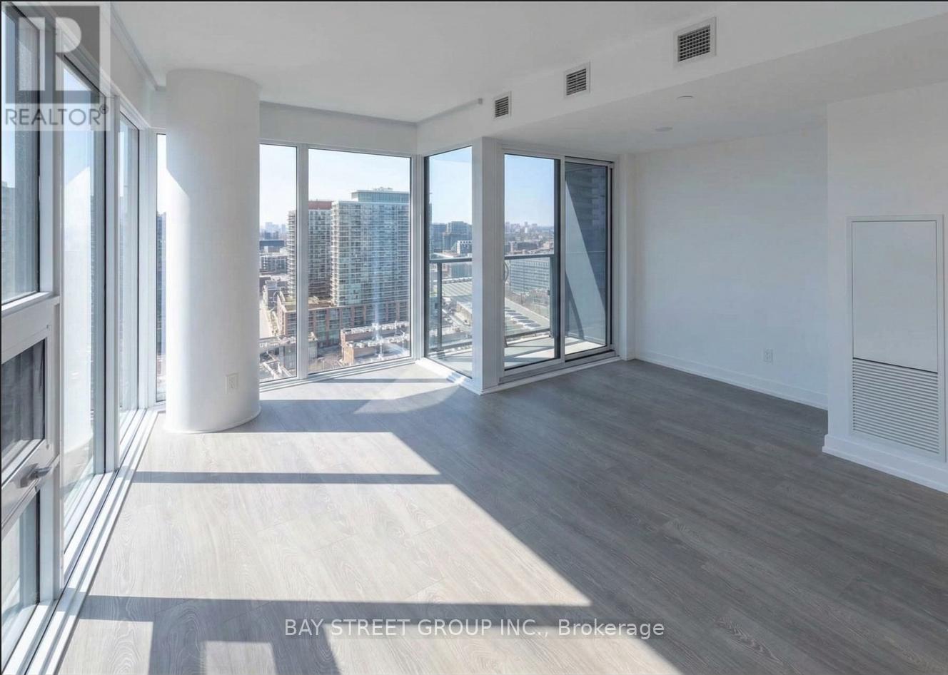 A spacious room with a view of the cityscape through large windows.