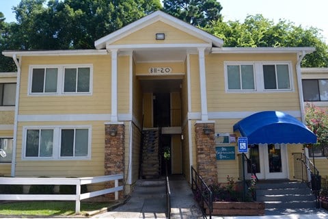 the front entrance of a yellow house with a blue awning