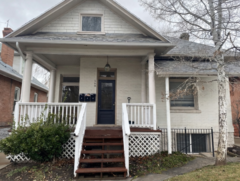 A white house with a black door and a small porch.