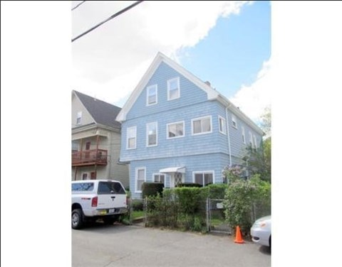 A blue house with a white car parked in front.