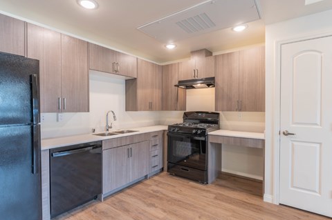 A kitchen with a black refrigerator and wooden cabinets.