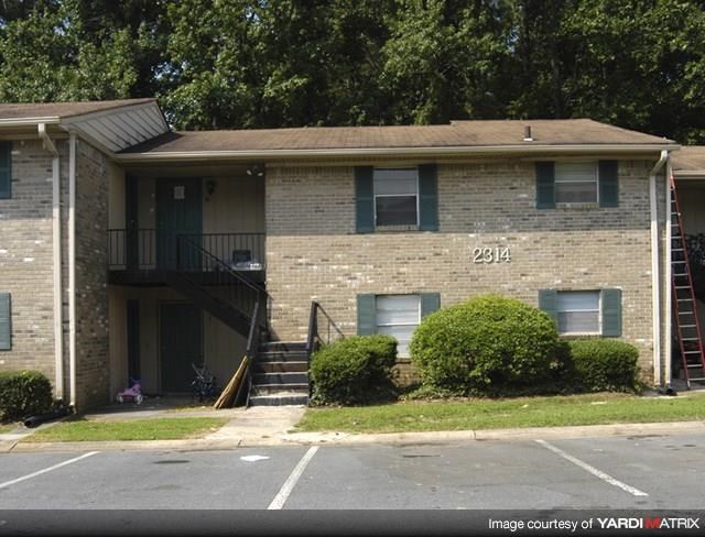 a brick apartment building with a porch and stairs