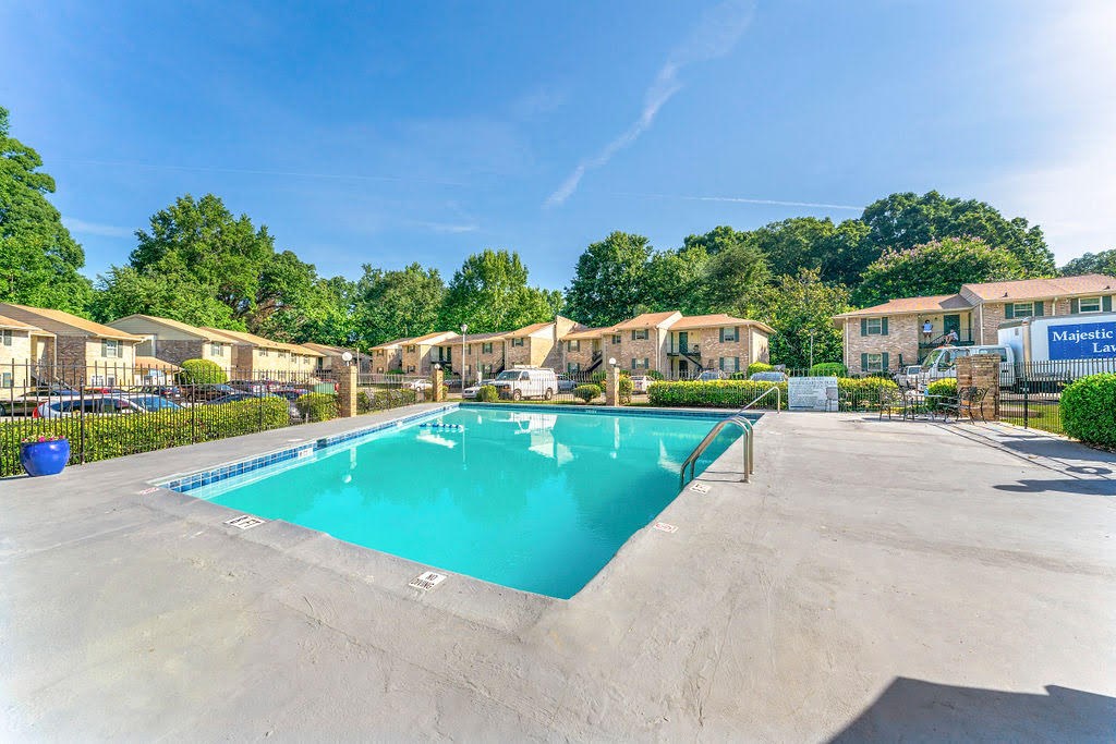 a swimming pool in a parking lot with apartments in the background
