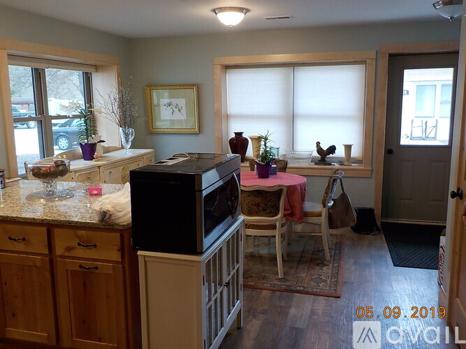 A kitchen with a black refrigerator, wooden cabinets, and a dining table with chairs.