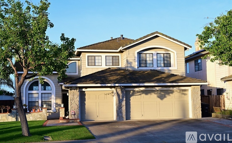 A two-story house with a garage and a tree in front.