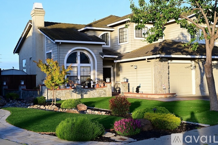 A large house with a stone wall and a landscaped front yard.