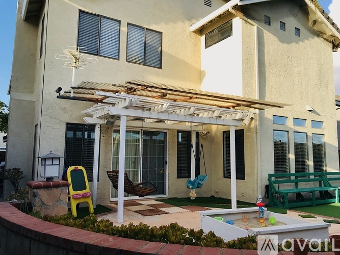 A house with a white pergola and a pool table in the backyard.