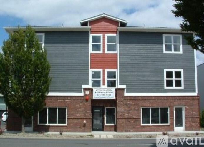 A building with a red and grey facade has a sign that reads "AVAILABLE".