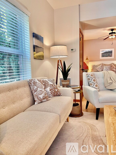 A living room with a beige couch, a side table with a lamp, and a ceiling fan.