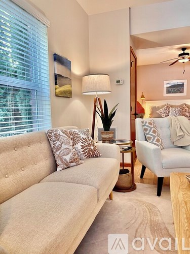 A living room with a beige couch, a side table with a lamp, and a ceiling fan.