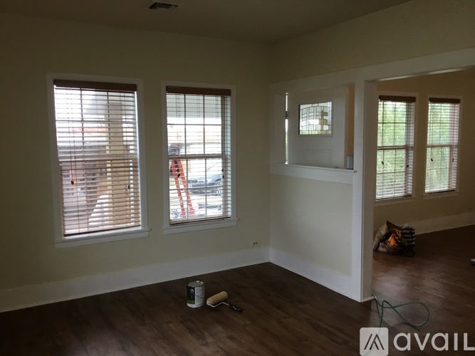 A room with wooden floors and two windows with blinds.