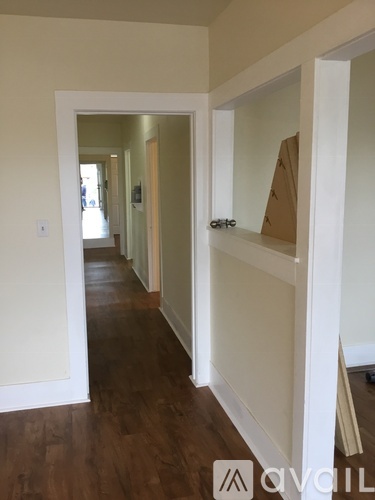 A hallway with wood floors and white walls.