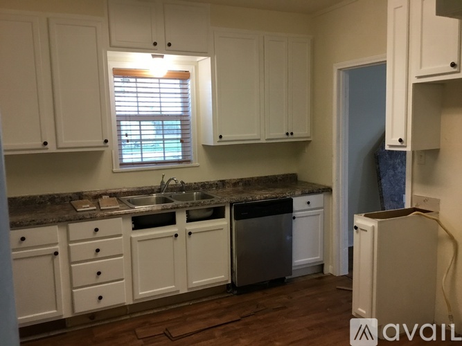 A kitchen with white cabinets and a granite countertop.