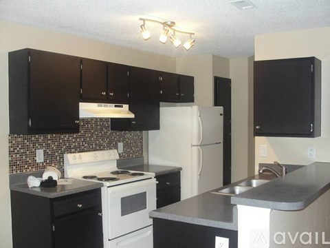 A kitchen with black cabinets and a white stove top oven.