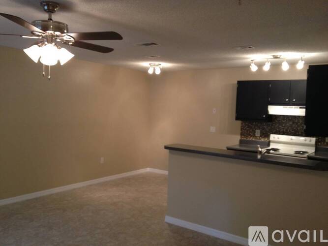 A room with a ceiling fan and a counter with a microwave.
