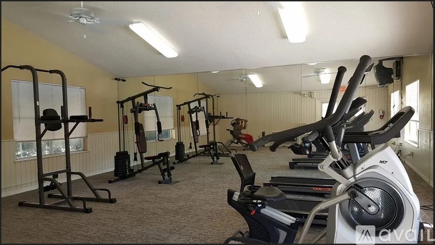 A gym with a variety of exercise equipment including treadmills, stationary bikes, and weight machines.