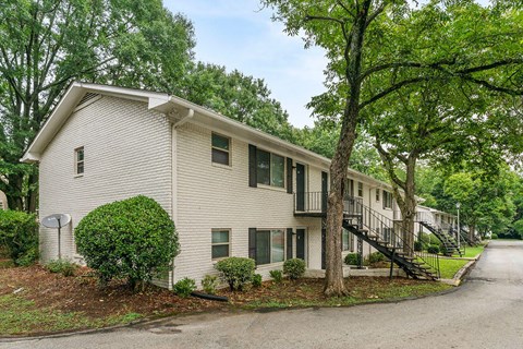 a white building with trees and a street in front of it
