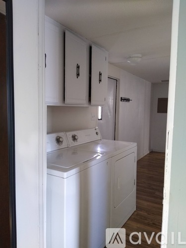 A white washing machine is in a small laundry room.