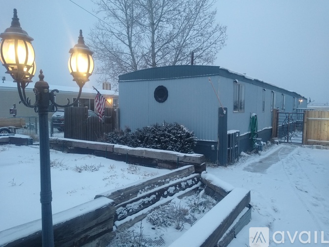 A snowy scene with a lamp post and a building in the background.