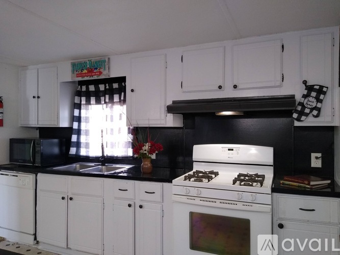 A kitchen with white cabinets and black countertops.