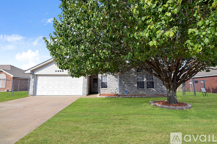 A tree with green leaves is in front of a house.