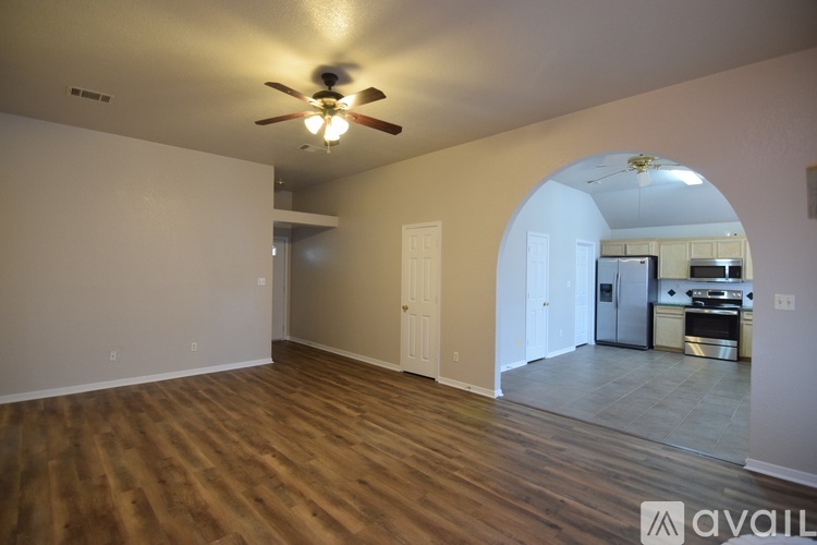 A spacious room with a ceiling fan and hardwood floors.
