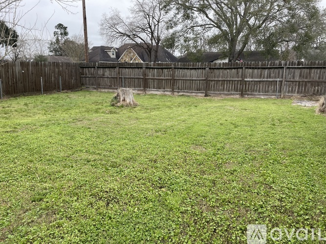 A backyard with a wooden fence and a grassy area.