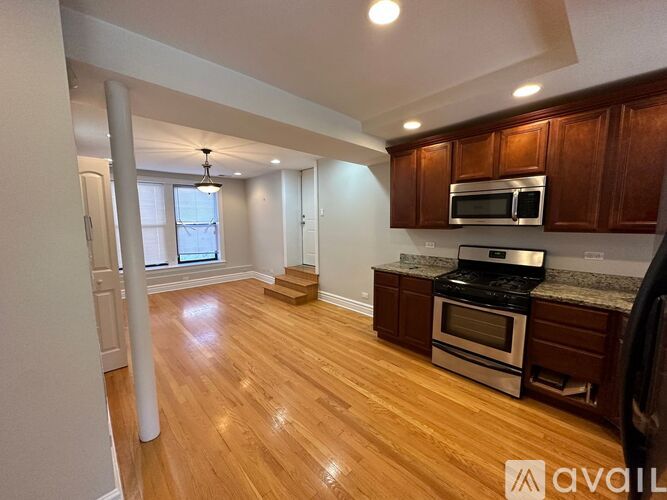 A kitchen with wooden floors and a stainless steel stove top oven.