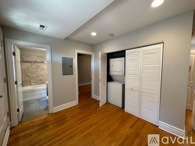 A room with wooden floors and white walls, with a door on the right side.