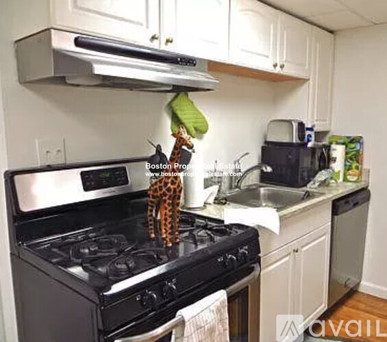 A kitchen with a black stove top and white cabinets.