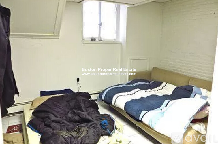 A bedroom with a bed covered in blankets and clothes.