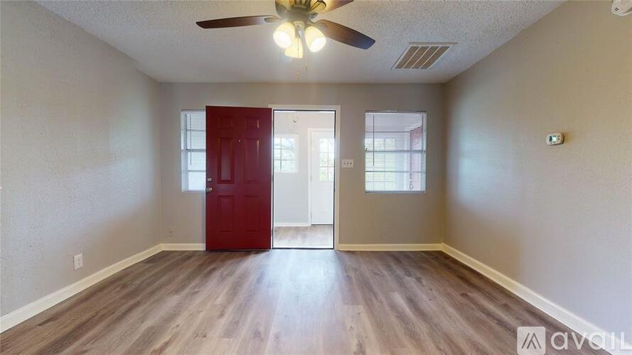 A room with a red door and a ceiling fan.