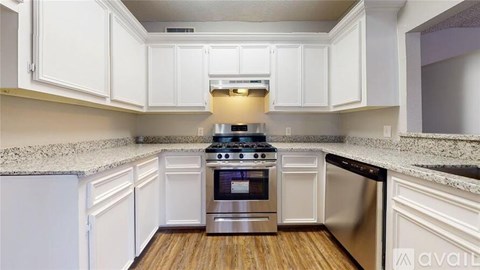A kitchen with white cabinets and a stainless steel stove.
