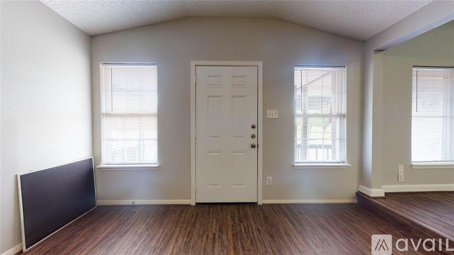 A room with a door, two windows, and a flat screen TV on the wall.