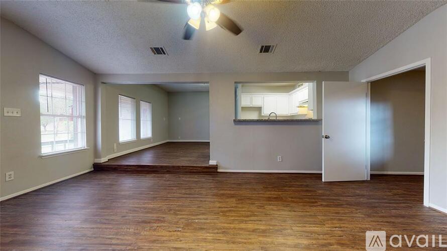 A spacious room with wooden floors and a large mirror on the wall.