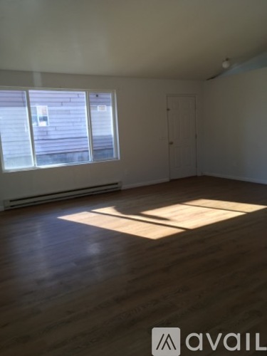 A room with wooden floors and a window letting in sunlight.
