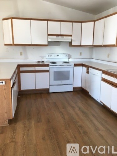 A kitchen with white appliances and wooden cabinets.