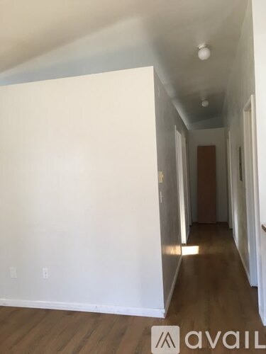 A long hallway with wood floors and white walls.
