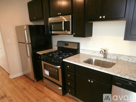 A kitchen with black cabinets and a stainless steel refrigerator.