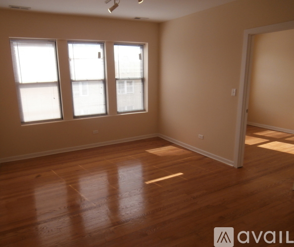 A room with wooden floors and three windows.