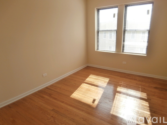 A room with wooden floors and a window with blinds.