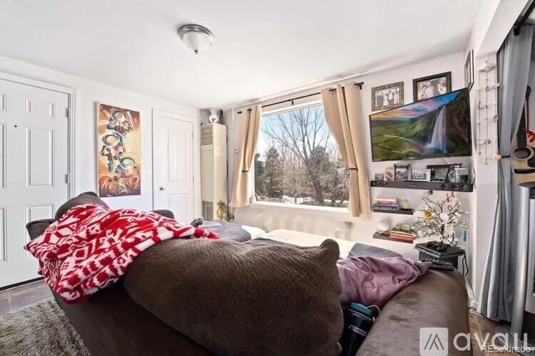 A living room with a brown couch and a window with curtains.