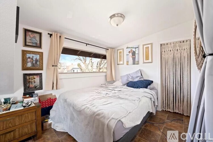 A bedroom with a large bed and a window with curtains.