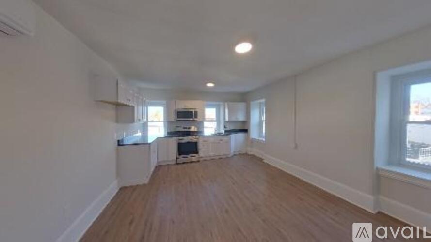A spacious room with wooden flooring and white walls.