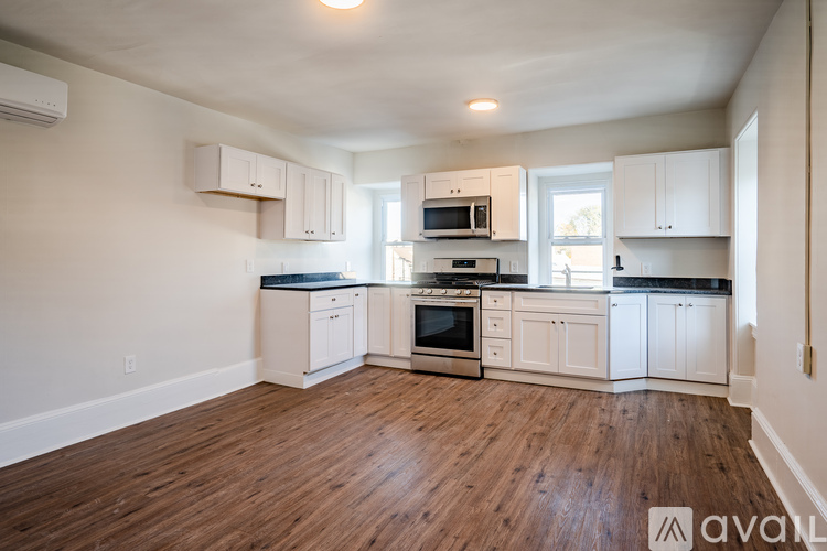 A kitchen with white cabinets and a wooden floor.