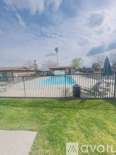 A pool surrounded by a fence with a sign that says "avail" in the foreground.