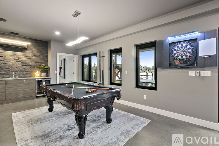 A pool table in a room with a dartboard on the wall.
